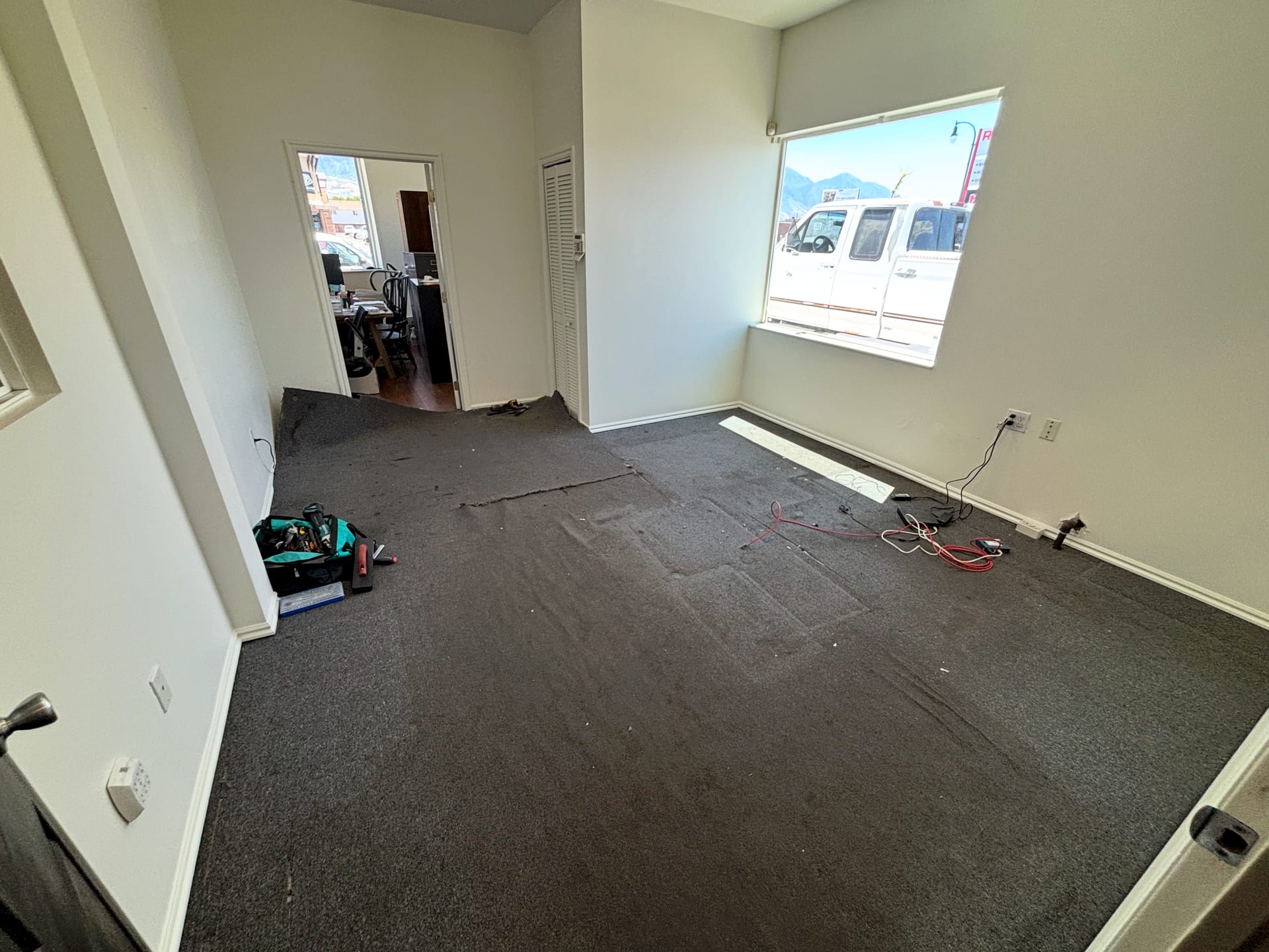 Bedroom with worn, stained carpet and loose floor wiring before new flooring was installed