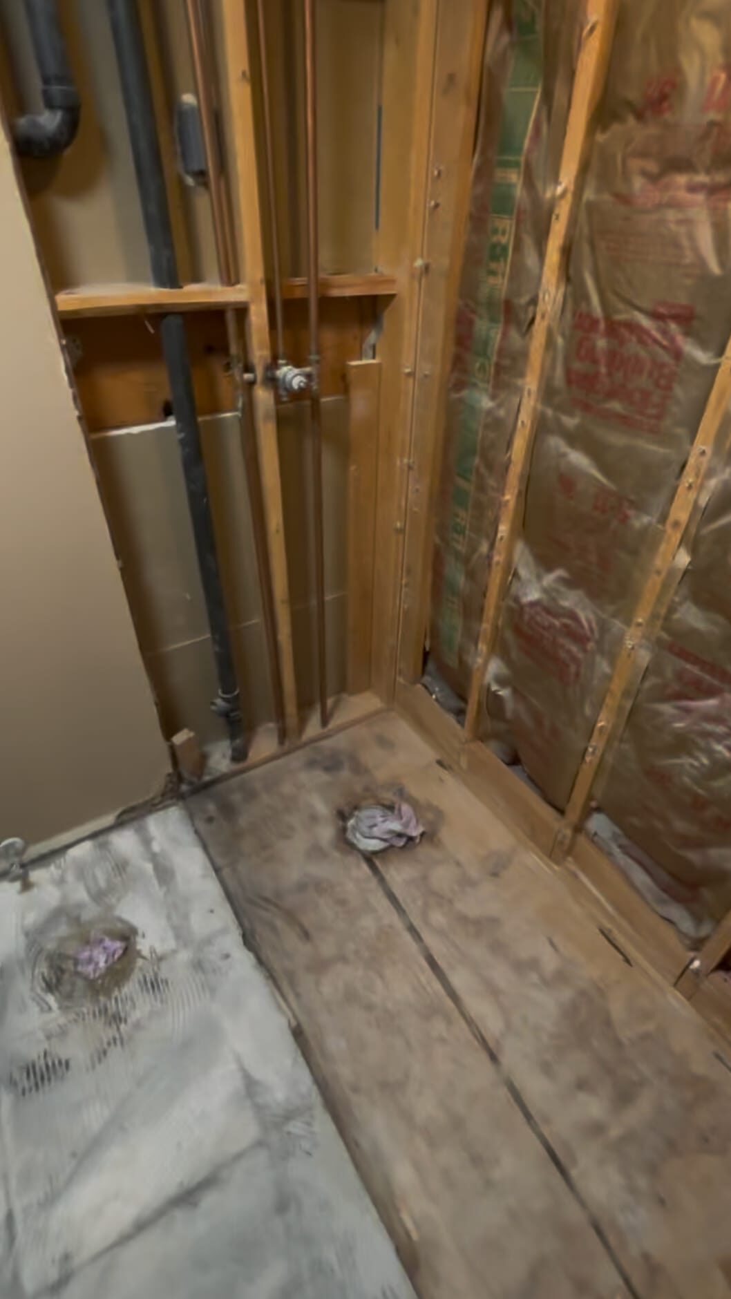 Bathroom shower stripped to bare studs and subfloor before tile work